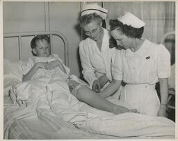 Nurses attending to child in hospital bed with sprained leg