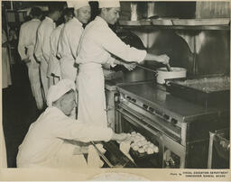 Instructor opening oven and students at cooktop, ca. 1954