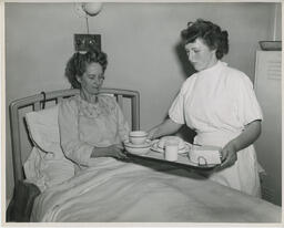 Nursing student serving a meal to a patient