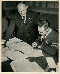 Student working on papers while instructor watches