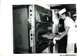 Student taking pies out of an oven