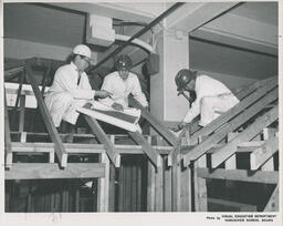 Students crouched on structure reading plans, ca. 1966