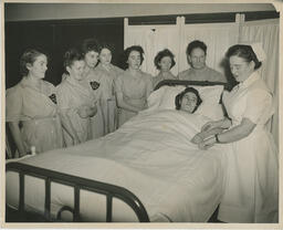 Nursing students watch as instructor treats patient