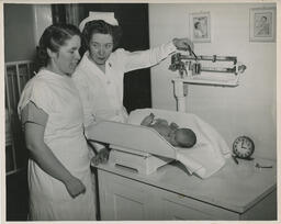 Baby being weighed by a nursing student as mother looks on
