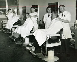 Group of barbering students giving customers haircuts, ca. 1949