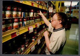 Student arranging cans in grocery store