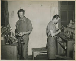 Two students working at shoe repair stations