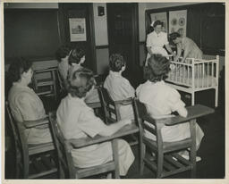 Nursing students in classroom with a crib