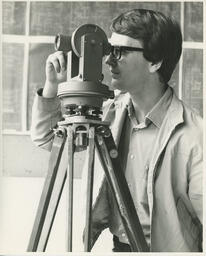 Student looks through a surveying tool, ca. 1972