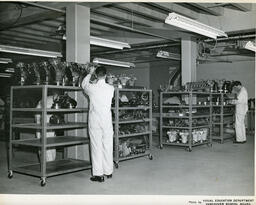 Diesel students arrange machine parts on shelves, ca. 1957
