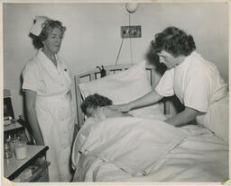 Nursing students helping patient in bed