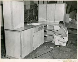 Student working on a corner kitchen cabinet, ca. 1958