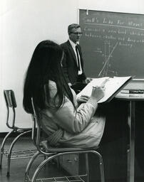 Student writing in binder at desk